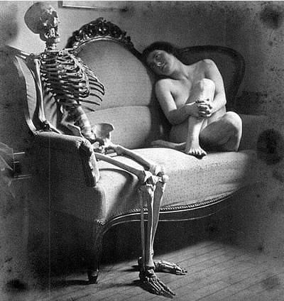 Naked woman on couch gazing at a seated skeleton